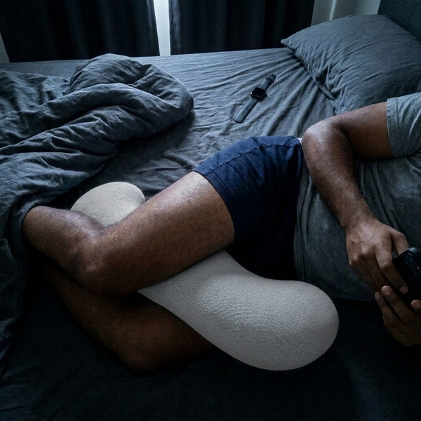 Man side sleeping with the grey Cuddle Curve pillow between his knees